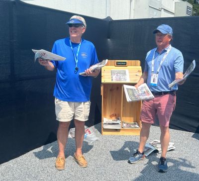 Former Washington Daily News publisher Brownie Futrell (left) and Pilot publisher David Woronoff hawk copies of The Pilot s U.S. Open Daily at the merchandise tent at the Championship. (The Pilot)